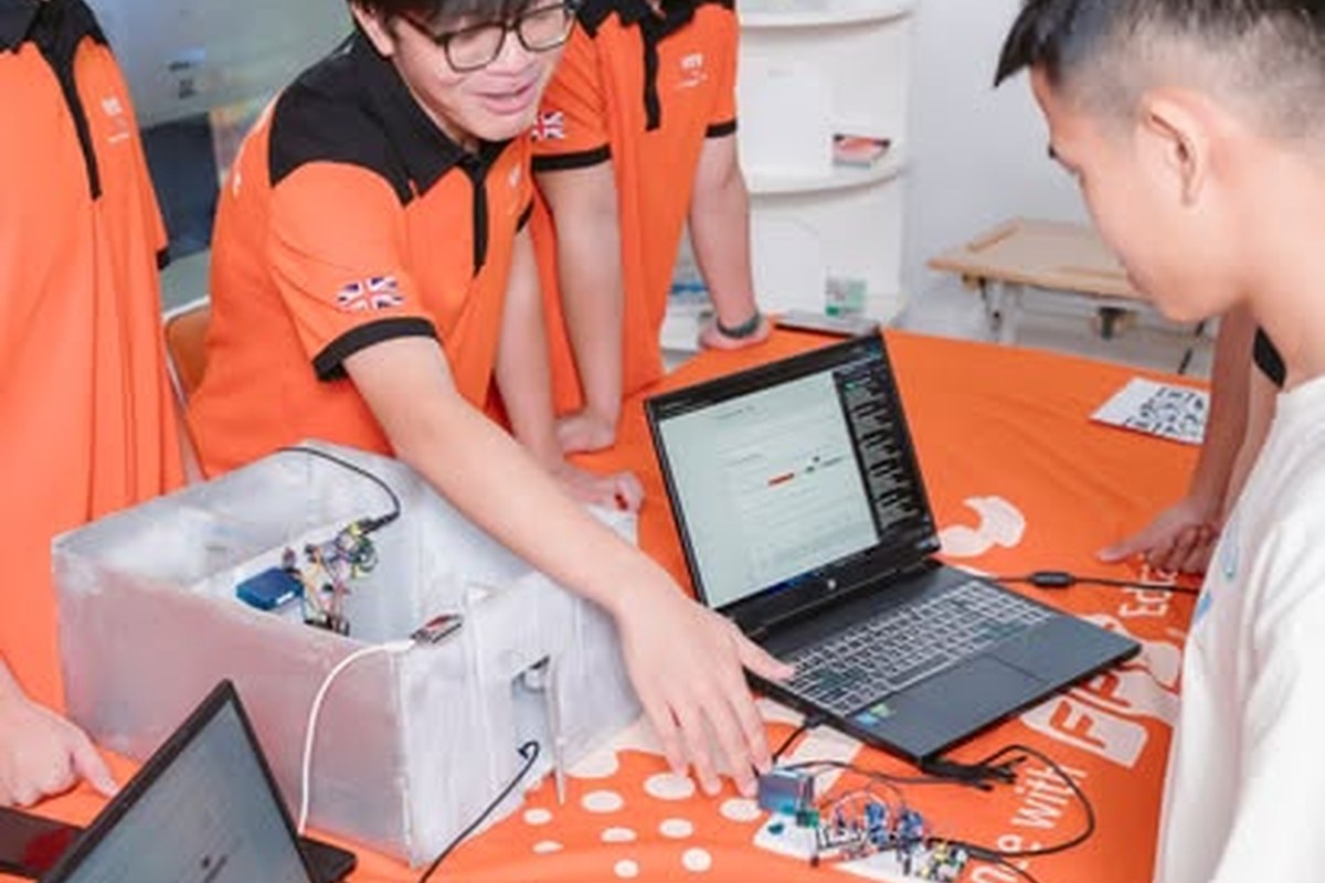 Sinh viên BTEC FPT vừa kiểm tra bảng mạch vừa quan sát mã lập trình và dữ liệu đo trên máy tính Sinh viên BTEC FPT kiểm tra bảng mạch, mã lập trình và dữ liệu đo